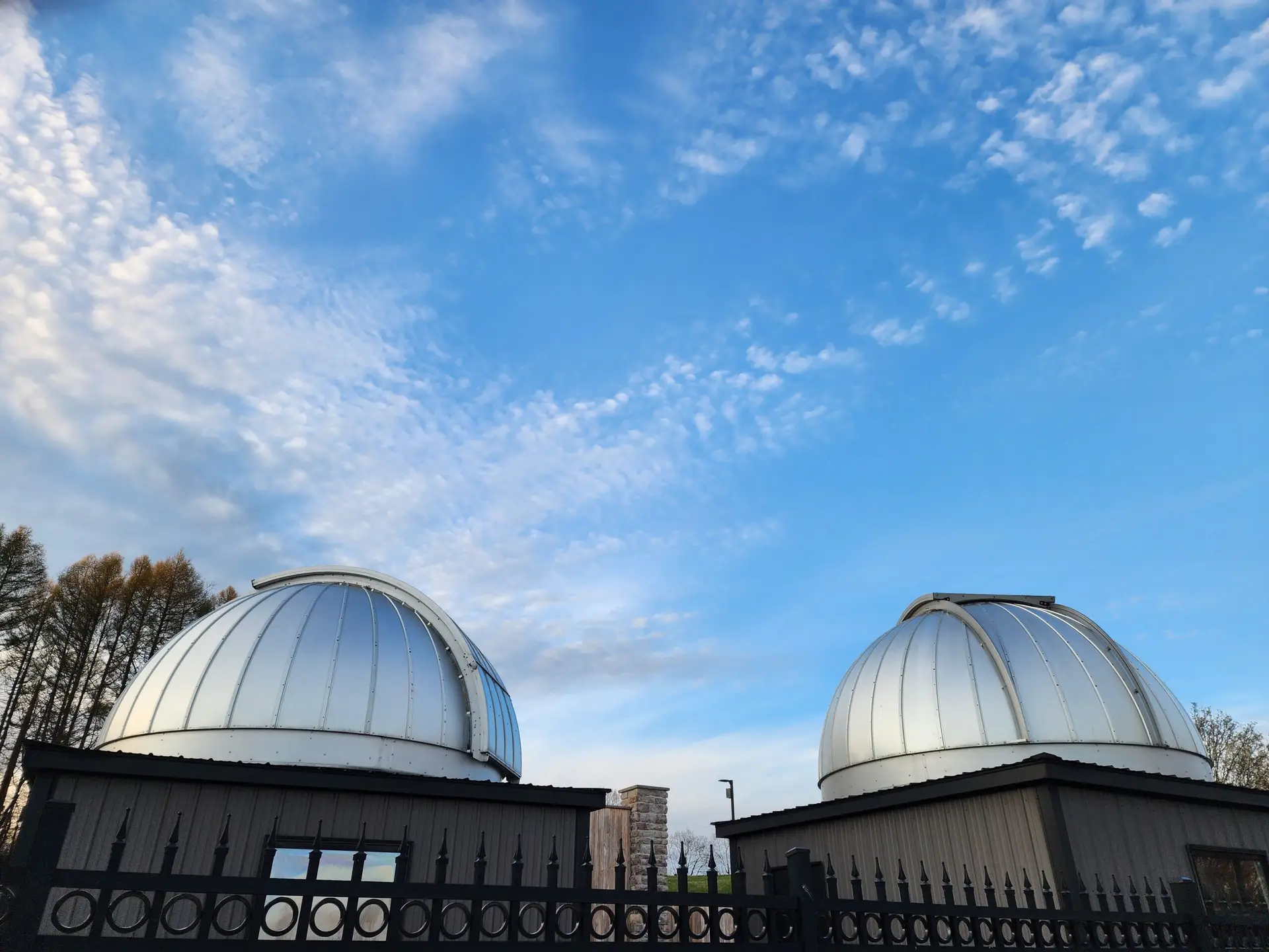 Two modern observatory domes under a blue sky, showcasing scientific exploration.